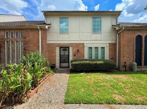 A two-story house with a front door, a small front yard, and a brick exterior. - 4BR townhome • King beds • Workspace • Pets OK! (Houston)