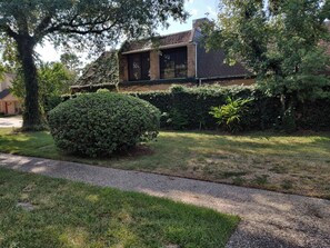 A residential house with a brick exterior, a large tree, and a well-maintained lawn. - 4BR townhome • King beds • Workspace • Pets OK! (Houston)