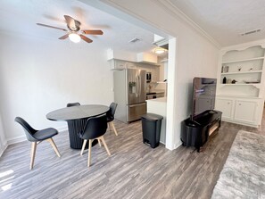 A modern kitchen with stainless steel appliances, a dining area with a round table and chairs, and a ceiling fan. - 4BR townhome • King beds • Workspace • Pets OK! (Houston)
