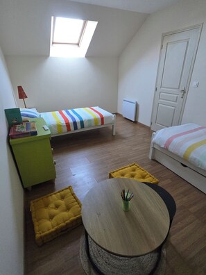 A small, well-lit room with a single bed, a desk, and a round table.