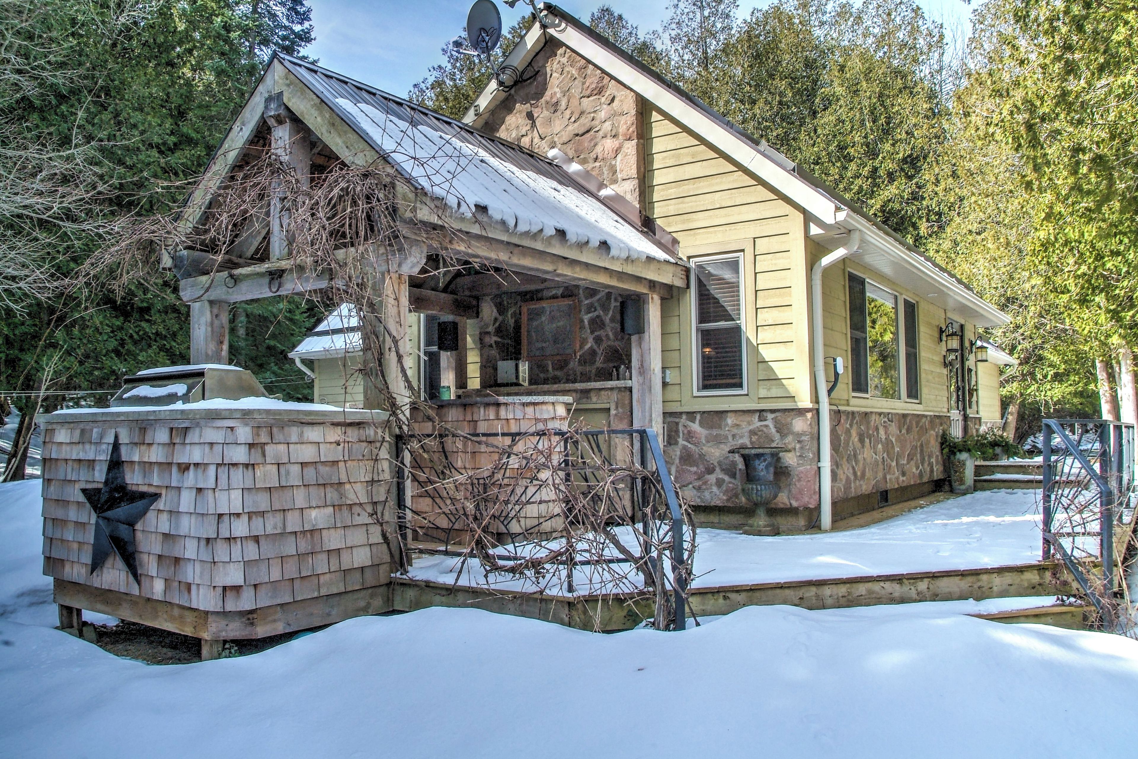 Une maison à deux étages, avec des fondations en pierre, un porche abrité et un toit recouvert de neige.