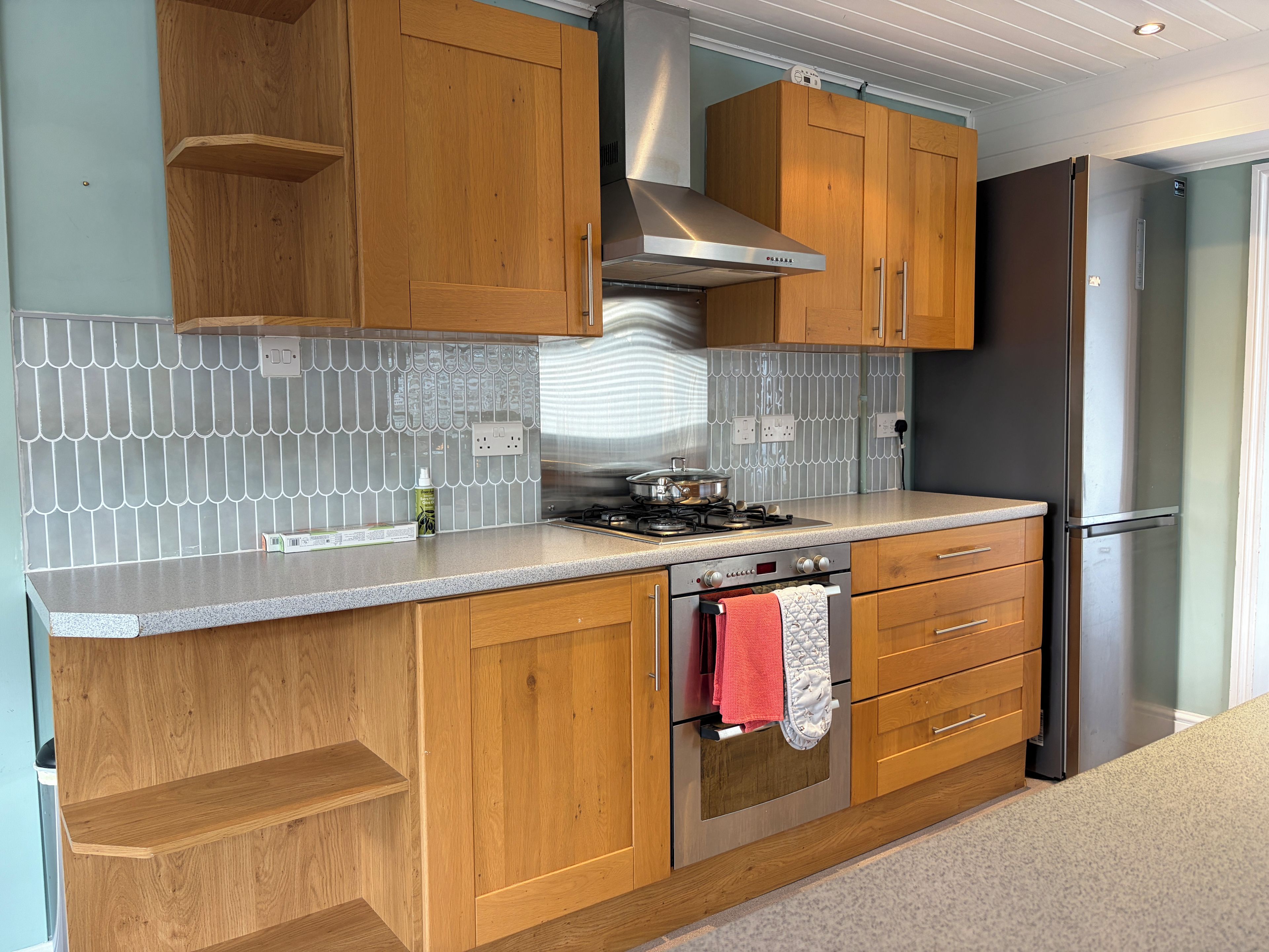 A kitchen with wooden cabinets, a stainless steel range hood, a gas stove, and a built-in oven.