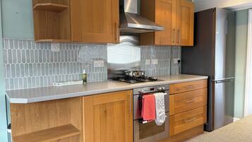 A kitchen with wooden cabinets, a stainless steel range hood, a gas stove, and a built-in oven.