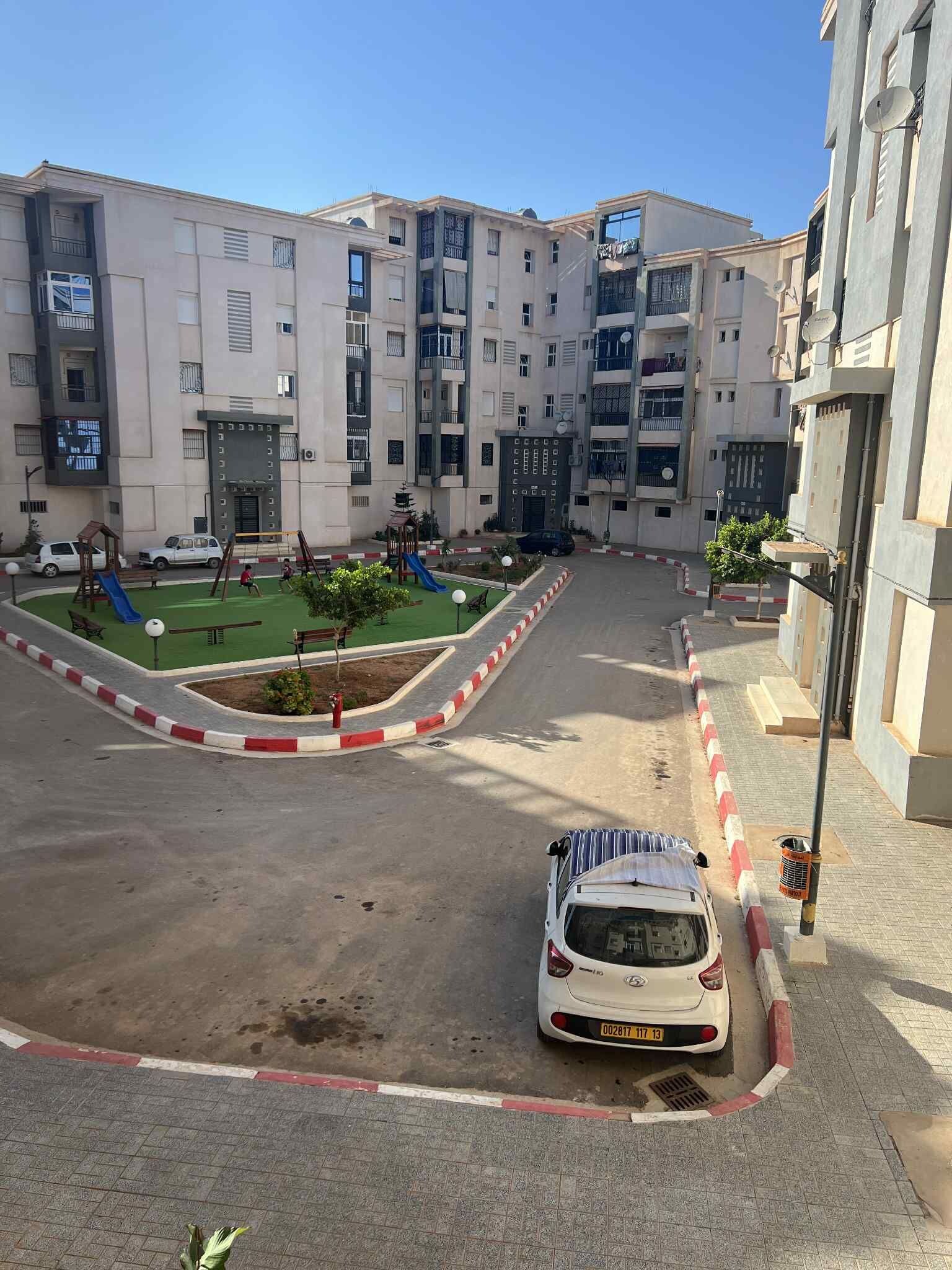 Un edificio residencial de varios pisos con un patio de recreo.