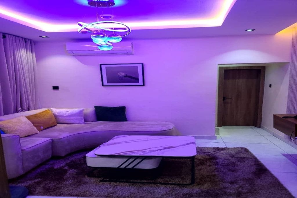 A modern living room with a sectional sofa, a small table, and a ceiling light fixture.