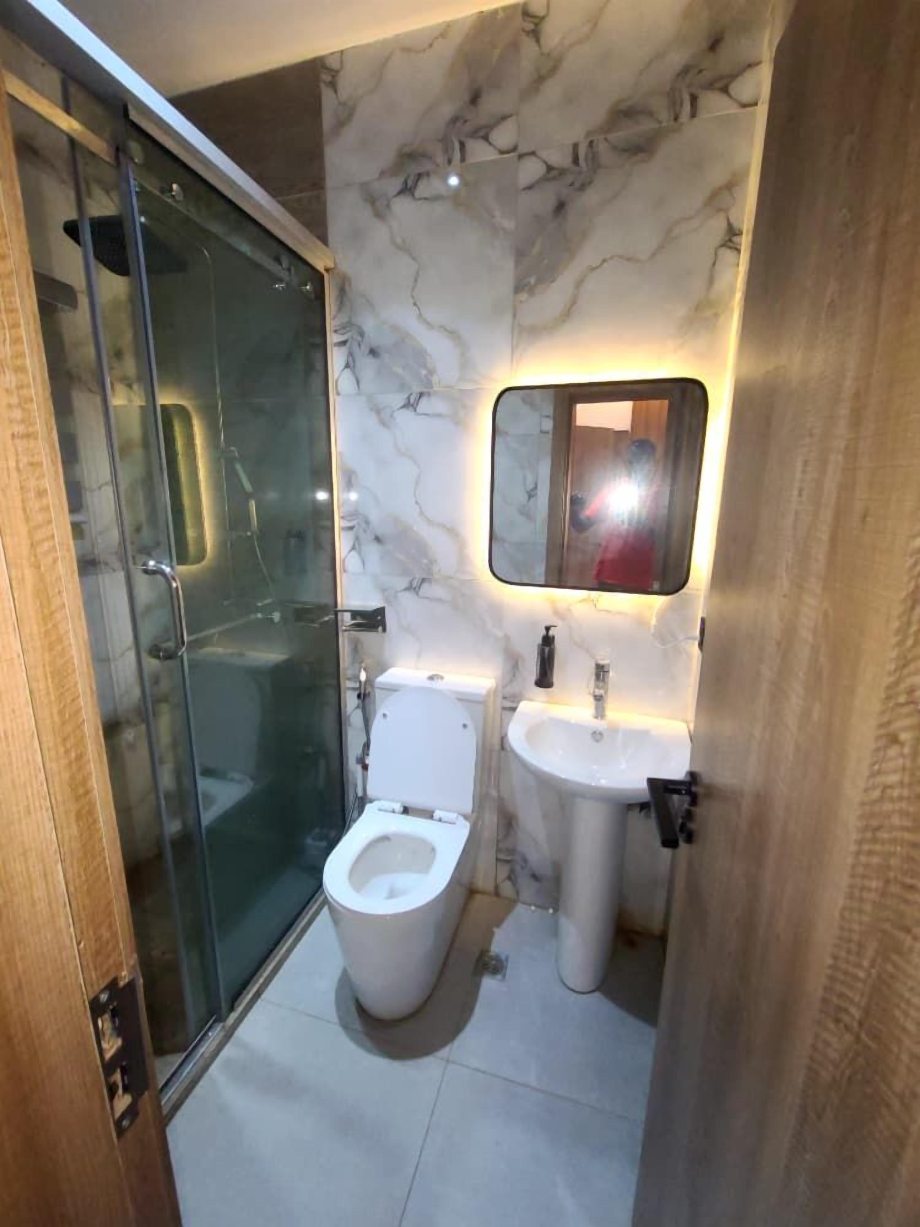 Une salle de bain moderne dotée d’une douche à parois de verre, de toilettes et d’un lavabo avec un pare-éclaboussures en marbre.