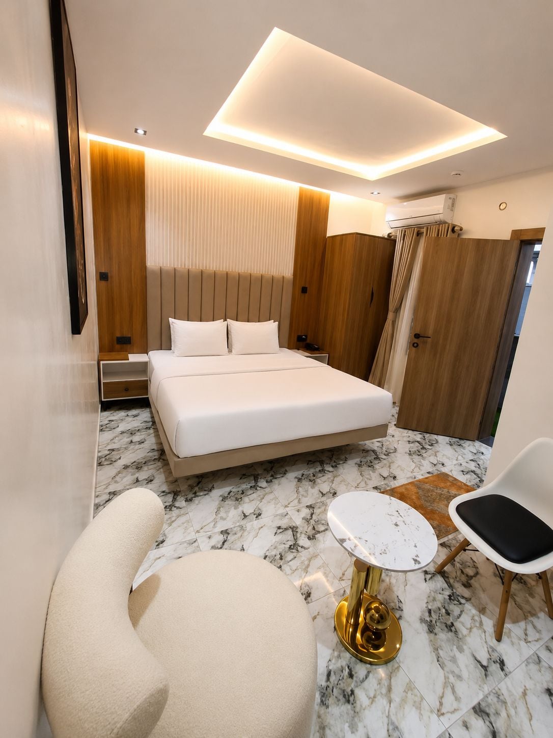 Una habitación de hotel moderna con una cama grande, una mesa redonda, una silla y un sofá.