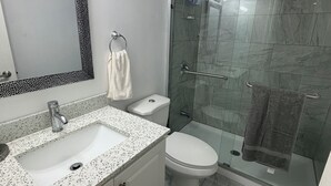 A bathroom with a white sink, toilet, and shower area. - Perfect basement apartment in Milton (Milton)