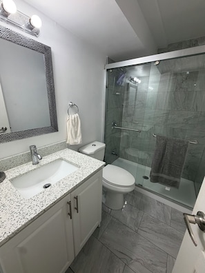 Ein Badezimmer mit weißem Waschbecken, einer Toilette und einer Duschkabine.