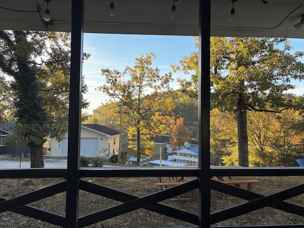 A view through a window with a wooden railing, featuring a residential area with houses and trees.