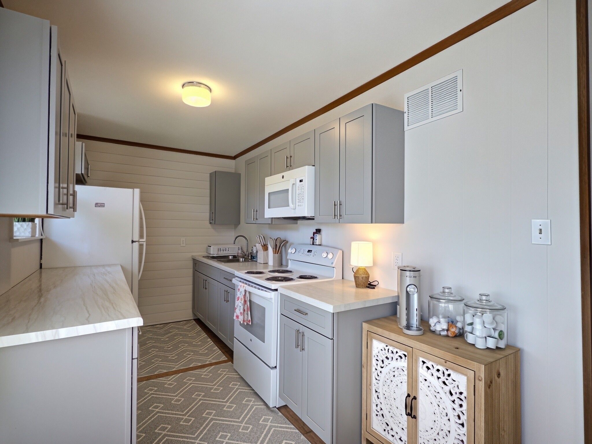 A compact kitchen with a refrigerator, microwave, stove, and sink.