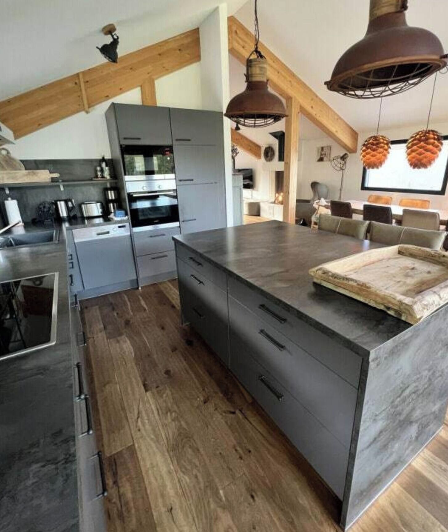 A modern kitchen with wooden beams, a large island, and pendant lighting.