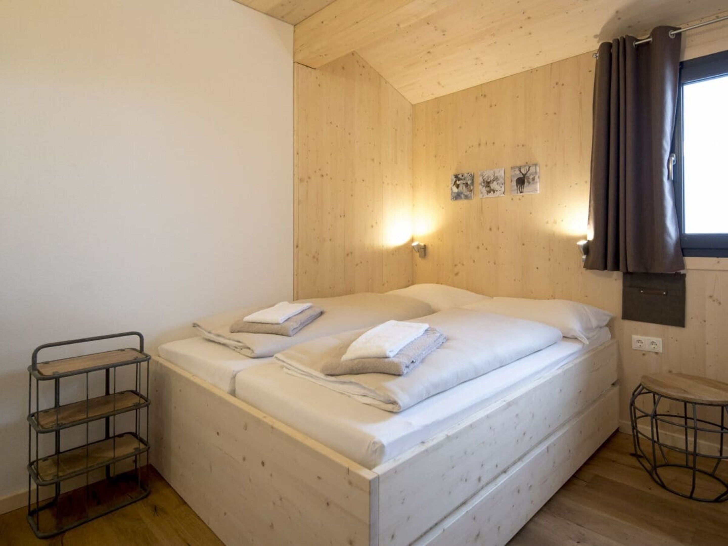 Un lit simple avec une tête de lit en bois, une étagère en métal et une petite table ronde.