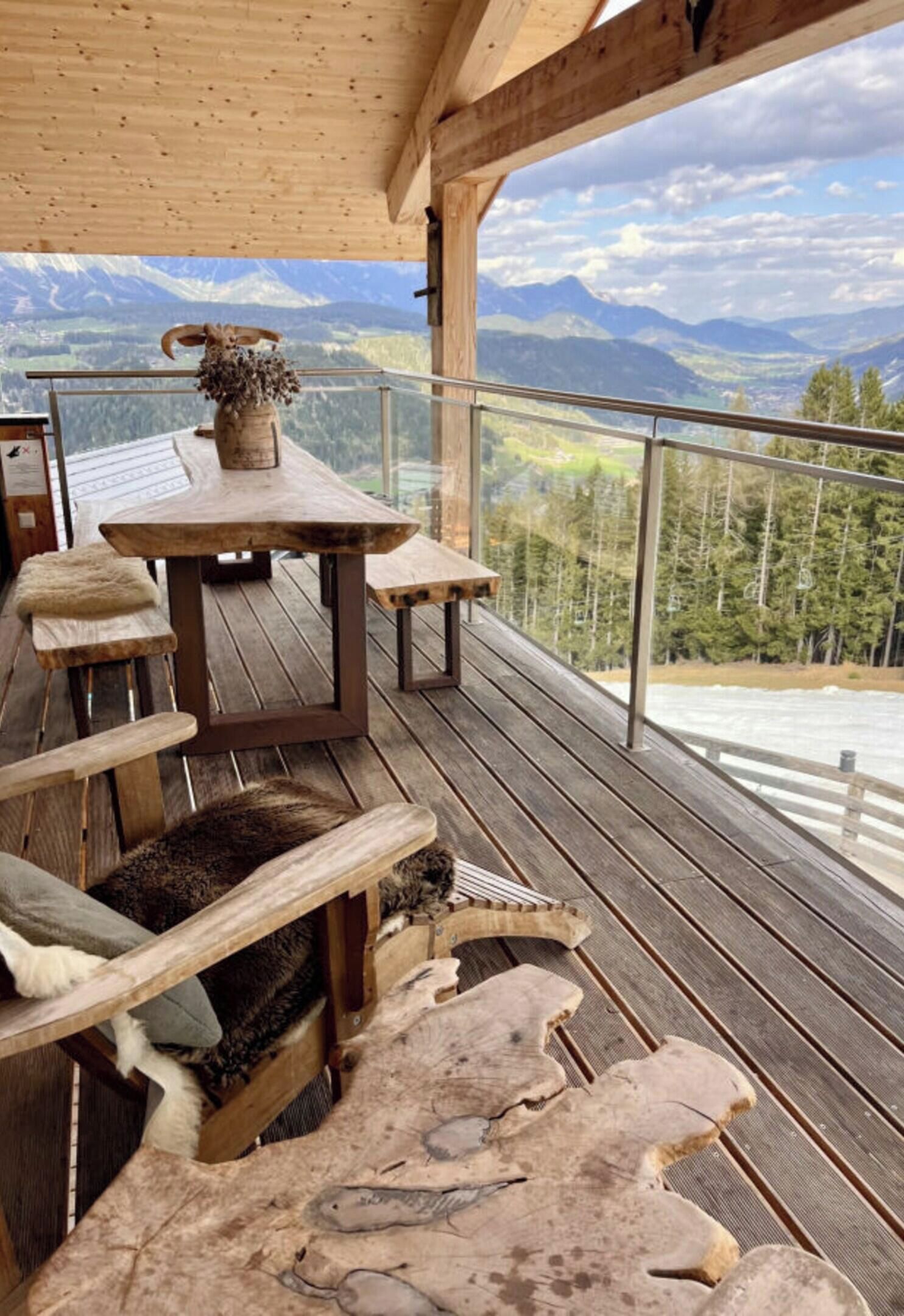 A wooden deck with a table and benches, overlooking a mountainous landscape.