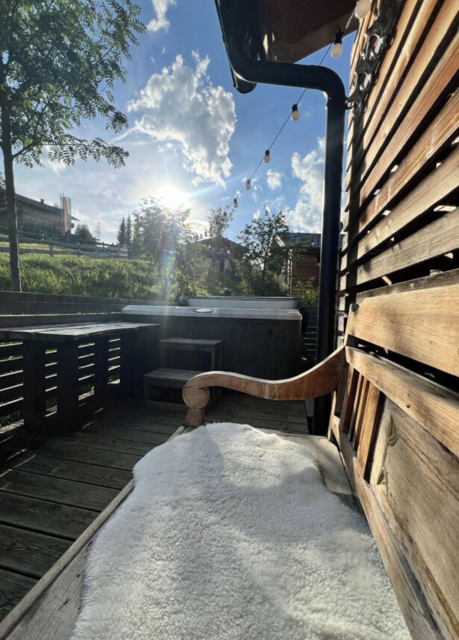 A wooden deck with a hot tub and a white rug.