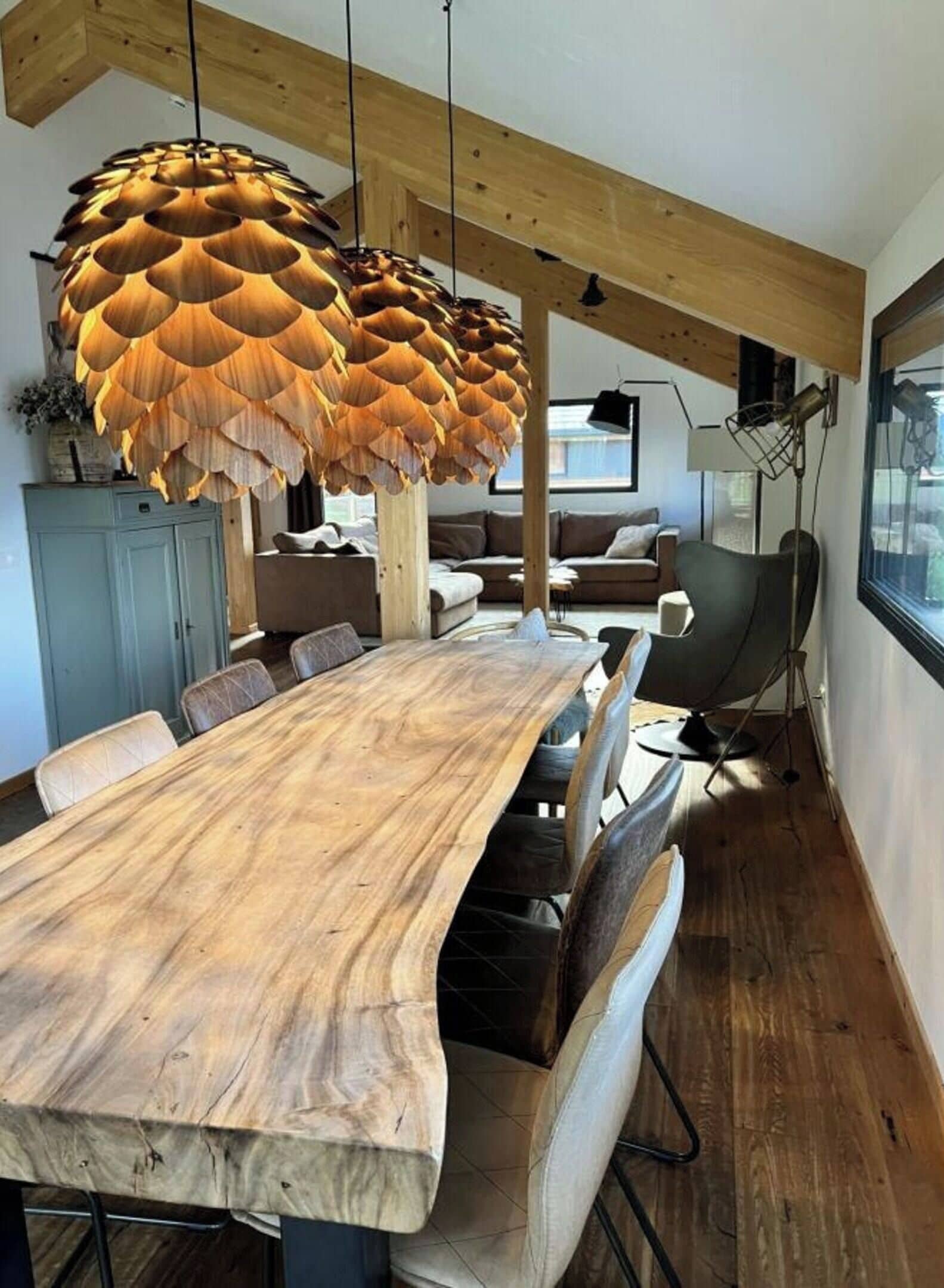 A dining area with a large wooden table, multiple chairs, and a unique hanging light fixture.