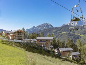Un complejo turístico de montaña con varias cabañas de madera, un telesilla y vistas a picos nevados.