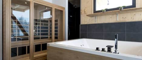 A modern bathroom with a freestanding bathtub, wooden cabinetry, and a window above the sink.