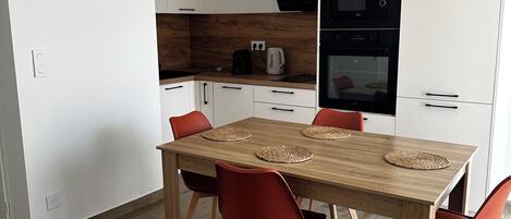 Une cuisine moderne avec des meubles blancs, une table à manger en bois et des chaises rouges.
