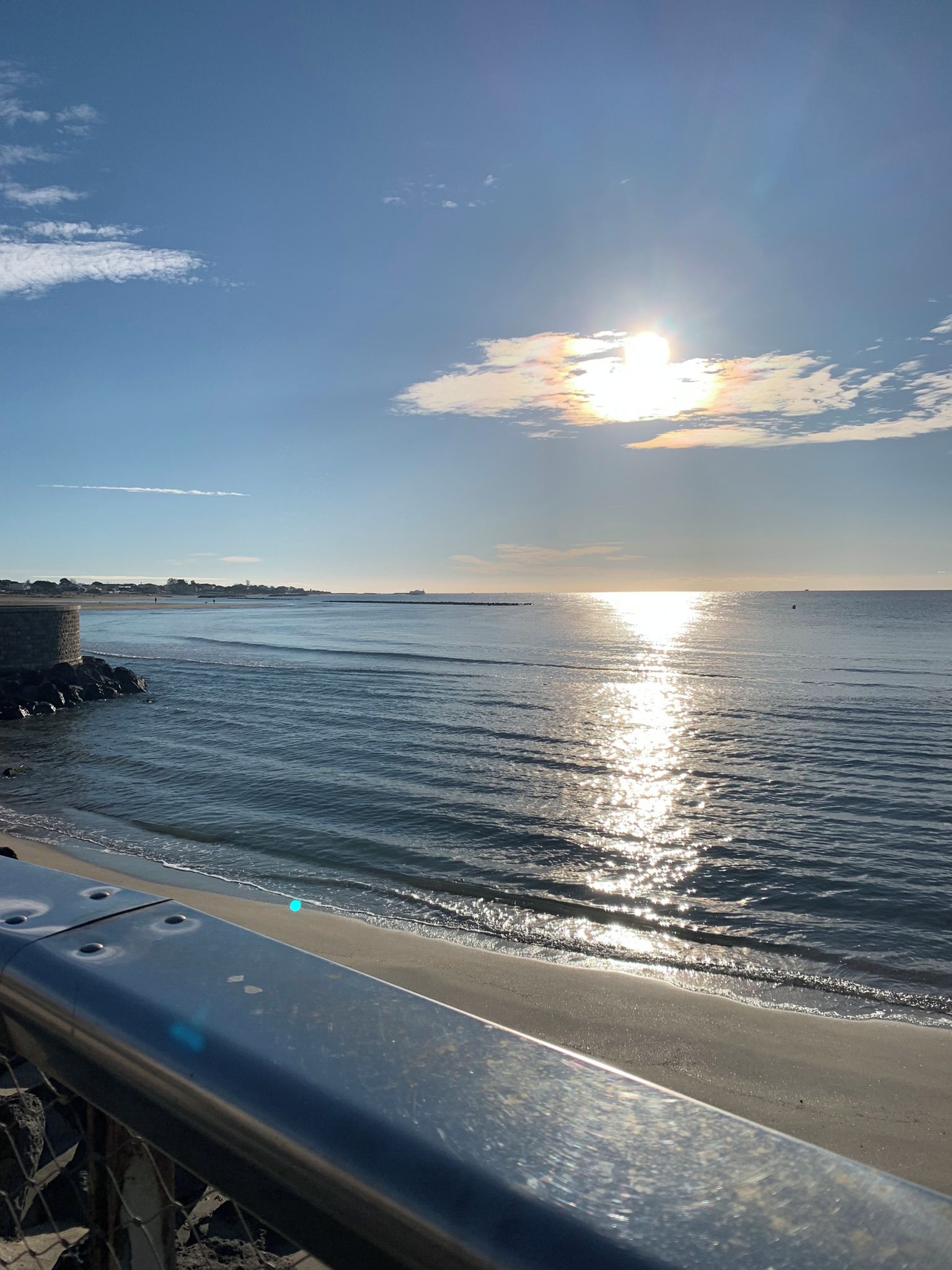 Un paysage côtier avec un ciel dégagé, une mer calme et une côte lointaine.
