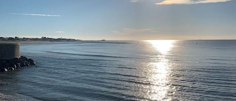 Escena costera con cielo despejado, mar en calma y una costa distante.