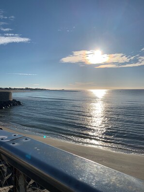 Un paysage côtier avec un ciel dégagé, une mer calme et une côte lointaine.