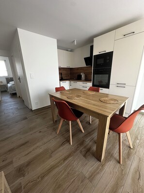 Une cuisine moderne avec des meubles blancs, une table à manger en bois et des chaises rouges.