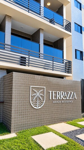Ein modernes Gebäude mit einem Schild, auf dem 'TERRAZZA BEACH RESIDENCE' steht.