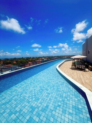 Ein Pool mit geschwungener Kante, Sonnenschirm und Blick auf die umliegende Landschaft.