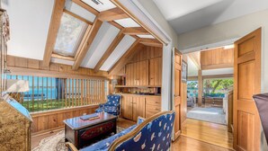 Ein Zimmer mit Holzbalken, Meerblick, einem blau gemusterten Sofa und einem Holzschrank.