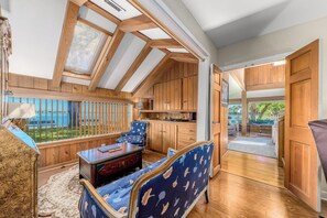 A room with wooden beams, a view of the sea, a blue patterned sofa, and a wooden cabinet. - OWL HOUSE RIVER RETREAT AT OLD COLORADO INN (Stuart)