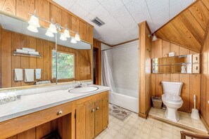 A wooden bathroom with a large mirror, vanity, bathtub, and toilet. - OWL HOUSE RIVER RETREAT AT OLD COLORADO INN (Stuart)