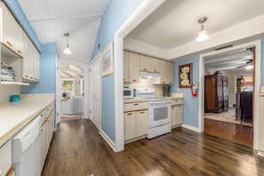 A compact kitchen with white cabinets, a microwave, an oven, and a sink.