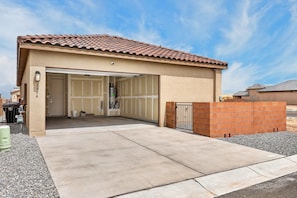 A single-story building with a tiled roof, a garage door, and a gated entrance.