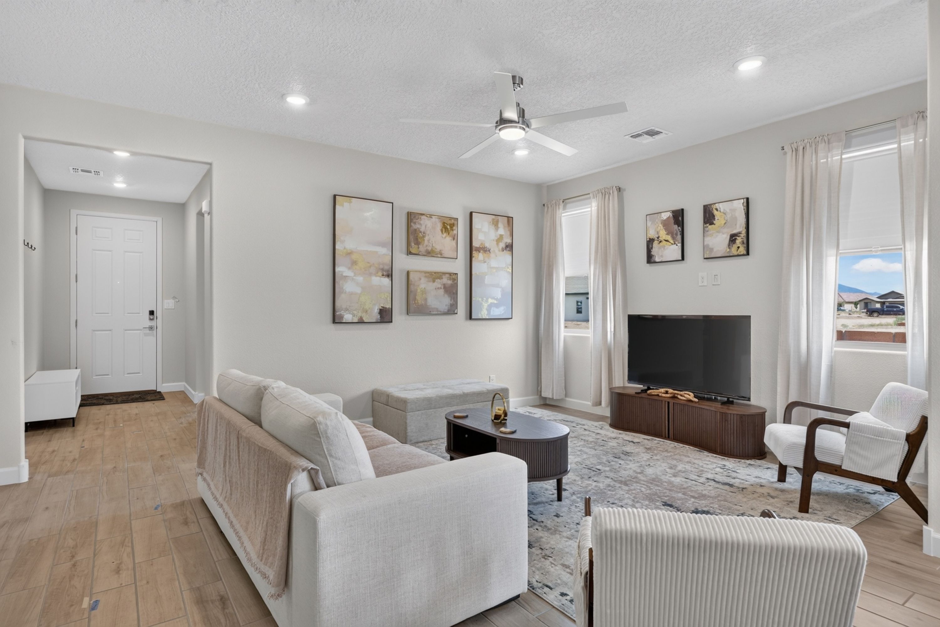 A modern living room with a sofa, armchairs, a coffee table, and a flat-screen TV.