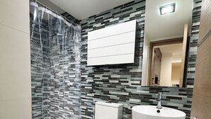 Een moderne badkamer met douche, toilet, wastafel en spiegel.