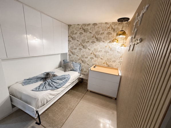 A compact bedroom with a bed, bedside table, and wardrobe.