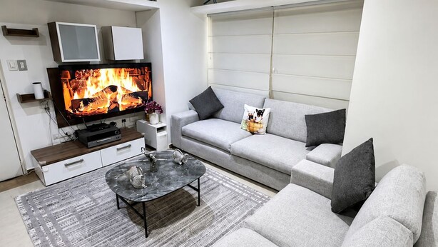 Een moderne woonkamer met een flatscreen televisie, een bank, een salontafel en een open haard.