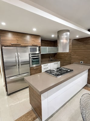 A modern kitchen with stainless steel appliances, a central island, and wooden cabinetry.