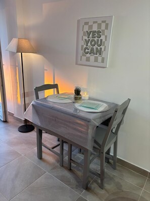 Ein Essbereich mit einem Tisch für zwei Personen, einer Lampe und einem motivierenden Wandbild.