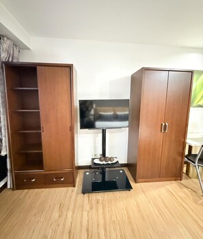A room with a television on a stand, wooden wardrobes, and a black floor. - Cozy Studio Unit condo in the heart of Makati with a perfect city view. (Makati)