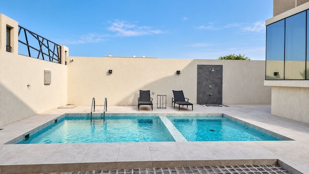 A rectangular swimming pool with two ladders, two lounge chairs, and a small table. - Azure 88 - Heated Private Pool Villa near Jebel Jais (Ras Al-Khaimah)