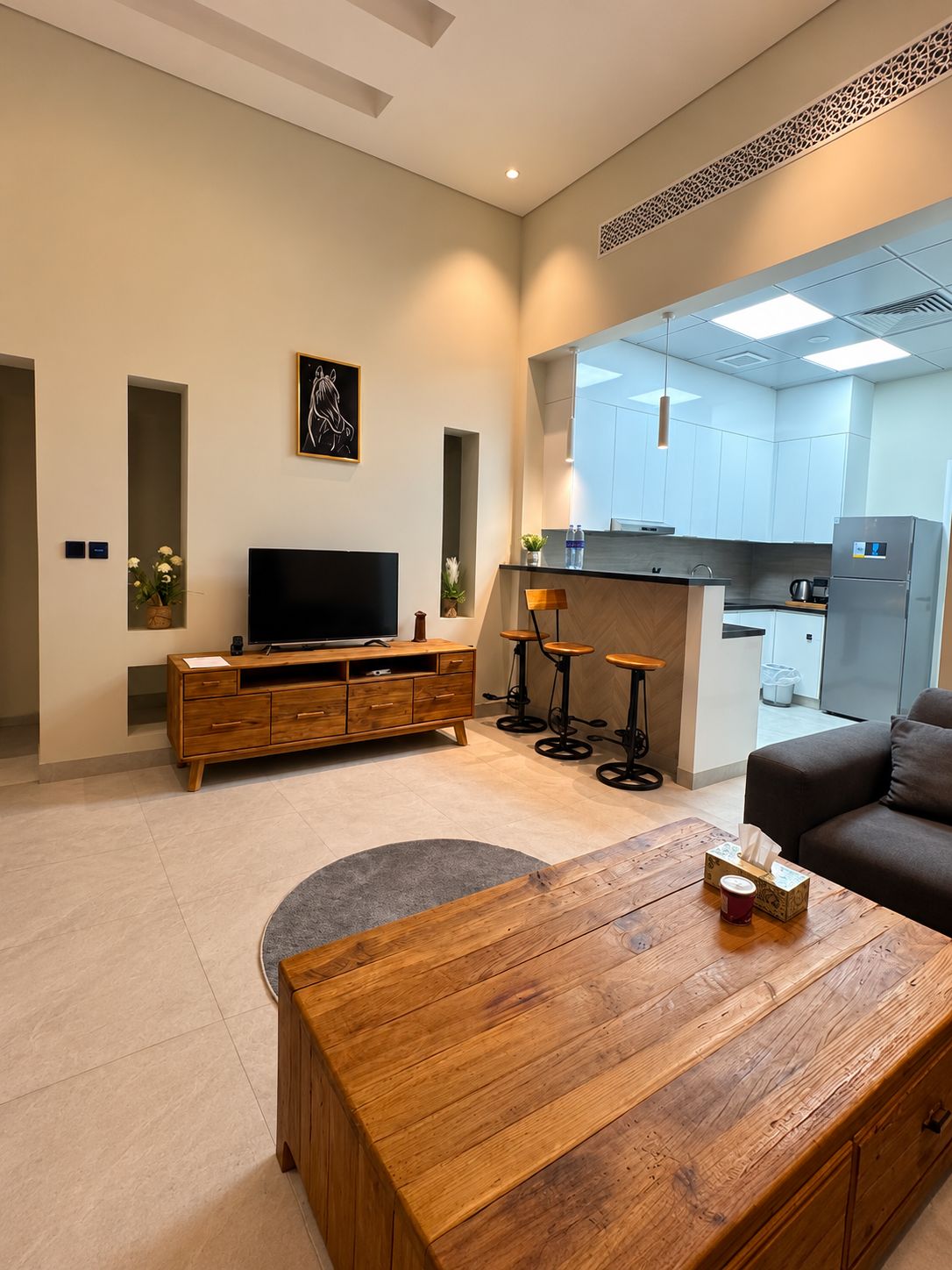 A modern living room with a wooden coffee table, a flat-screen TV, and a sofa.