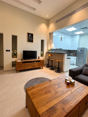 A modern living room with a wooden coffee table, a flat-screen TV, and a sofa. - Azure 88 - Heated Private Pool Villa near Jebel Jais (Ras Al-Khaimah)