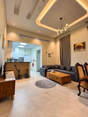 A modern living room with a sofa, coffee table, and bar stools.