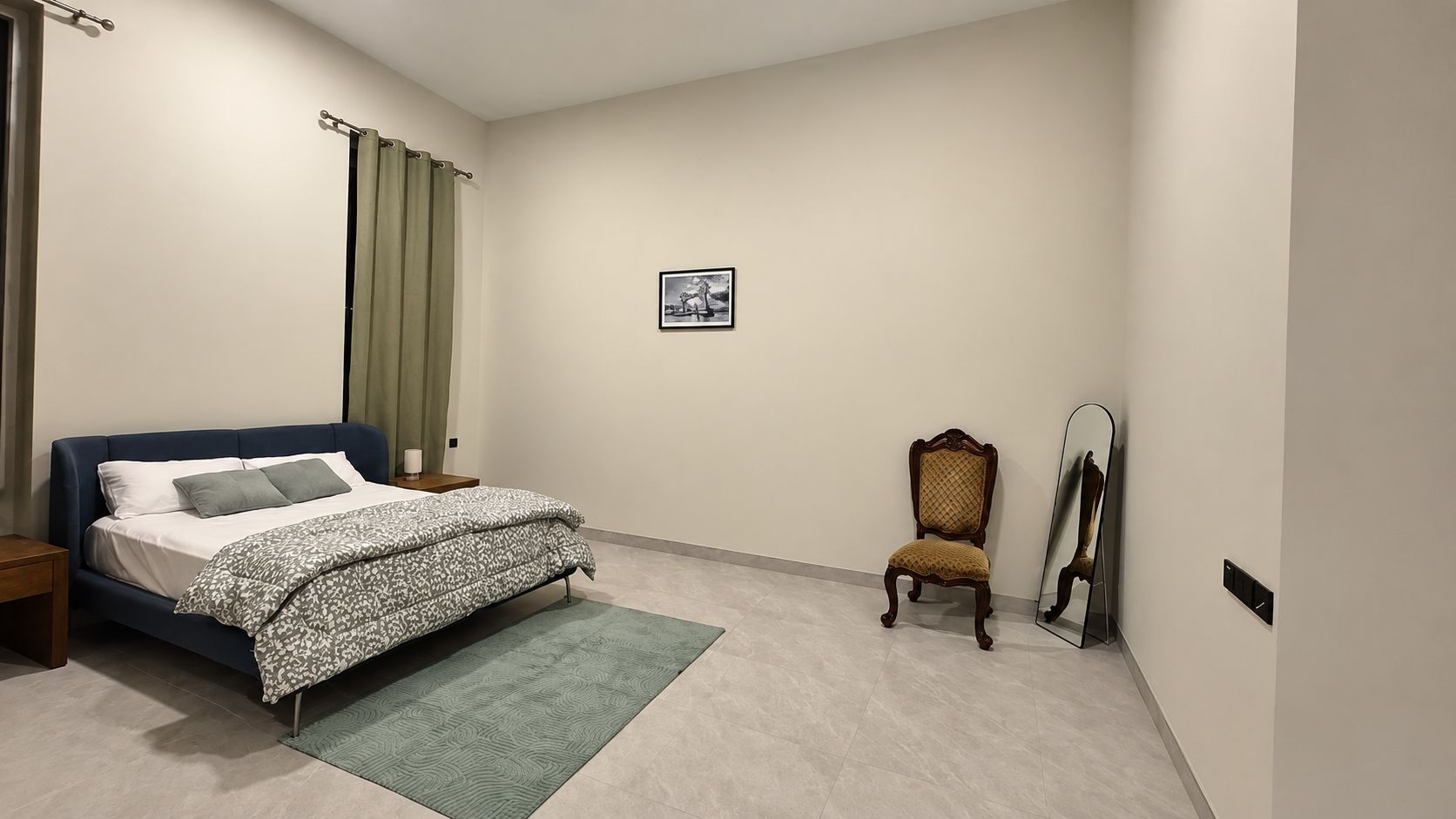 A bedroom with a bed, a chair, a mirror, and a picture on the wall.