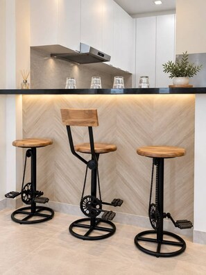 A modern kitchen with three bar stools featuring wooden seats and black metal frames with gear pedals. - Azure 88 - Heated Private Pool Villa near Jebel Jais (Ras Al-Khaimah)