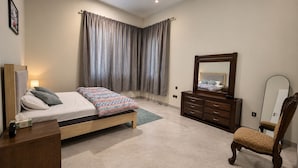 A bedroom with a bed, dresser, chair, and a large mirror. - Azure 88 - Heated Private Pool Villa near Jebel Jais (Ras Al-Khaimah)