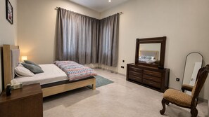 A bedroom with a bed, dresser, chair, and a large mirror. - Azure 88 - Heated Private Pool Villa near Jebel Jais (Ras Al-Khaimah)