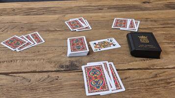 Ein Holztisch mit Spielkarten und einer schwarzen Box mit dem Aufdruck '100% Plastik Spielkarten'.